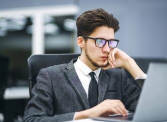 Business manager in glasses works on his laptop in the office. Freelancer working from a laptop